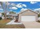 Tan house with white garage door, landscaped yard, and walkway at 6201 Cedarbrook N Dr, Pinellas Park, FL 33782