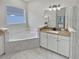 Elegant bathroom with corner bathtub, granite countertop, and white cabinets at 4739 Butler National Dr, Wesley Chapel, FL 33543