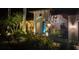 Night view of home's entryway, illuminated landscaping, and palm trees at 6720 The Masters Ave, Lakewood Ranch, FL 34202