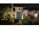 Night view of home's entry with landscape lighting and palm trees at 6720 The Masters Ave, Lakewood Ranch, FL 34202