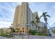 Upscale condo building with tropical landscaping, fountain, and luxury entrance, under a blue sky with wispy clouds at 750 N Tamiami Trl # 814, Sarasota, FL 34236