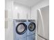 Convenient laundry area with modern washer, dryer, and white cabinets at 750 N Tamiami Trl # 814, Sarasota, FL 34236