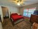 Cozy bedroom with a red bedspread and ceiling fan at 2022 Peaceful Palm St, Ruskin, FL 33570