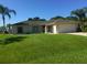 Charming single-story home with a lush green lawn, palm trees, and a two-car garage at 4666 Laramie Cir, North Port, FL 34286