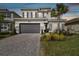 Two-story house with gray siding, stone accents, and a 3-car garage at 3135 Great Banyan Way, Wesley Chapel, FL 33543