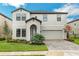 Two-story house with a light beige exterior, landscaping, and a three-car garage at 13015 Homestead Ln, Parrish, FL 34219