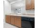 Kitchen boasts wood cabinets, a black dishwasher, and a view to the living area at 3473 Parkridge Cir # 17-101, Sarasota, FL 34243