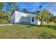 Modern house exterior with a white finish and gray accents, featuring a grassy lawn and palm tree at 3580 Richardson Sw St, North Port, FL 34288