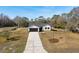 Aerial view of a modern farmhouse with driveway and American flag at 4039 Meadow Run Ln, Wesley Chapel, FL 33543