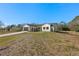 White farmhouse exterior with dark brown garage door and landscaping at 4039 Meadow Run Ln, Wesley Chapel, FL 33543