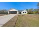 White farmhouse exterior with dark brown garage door, landscaping, and driveway at 4039 Meadow Run Ln, Wesley Chapel, FL 33543