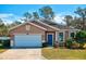 Tan one-story house with white garage door and blue front door, surrounded by green lawn at 2729 Walden Woods Dr, Plant City, FL 33566