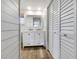 Bathroom with double vanity, white cabinets, and wood-look tile flooring at 7326 Shepherd St, Sarasota, FL 34243