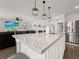 Modern kitchen island featuring a stainless steel faucet, white cabinets, and pendant lighting fixtures at 9189 Royal River Cir, Parrish, FL 34219