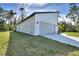 View of the modern white home showcasing a two-car garage and landscaped front yard at 2610 Valkaria Ave, North Port, FL 34286