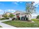 One-story home with red door, landscaping, and driveway at 30350 Grymes Dr, Wesley Chapel, FL 33545