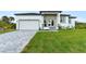 Modern one-story home with gray-tone exterior, white garage door, and a landscaped lawn at 13438 Mcintosh Ave, Port Charlotte, FL 33981