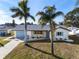 Well-maintained home with a green lawn, palm trees, and a light blue garage door at 105 12Th Sw St, Ruskin, FL 33570