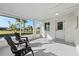 A screened-in porch with chairs, a white-painted brick wall, access door, and a view of the palm-tree-lined lawn at 105 12Th Sw St, Ruskin, FL 33570