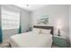 Comfortable bedroom with a gray headboard bed, two turquoise bedside tables, and natural light at 11400 Burgundy Dr, Venice, FL 34293