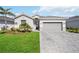 Charming one-story home featuring a well-manicured lawn, elegant brick driveway, and a two-car garage at 11400 Burgundy Dr, Venice, FL 34293