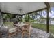 View of back patio with outdoor dining table, overlooking fenced yard and waterfront at 289 Whisper Lake Rd, Palm Harbor, FL 34683