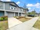 Charming townhome exterior with gray siding, a one-car garage, a well-manicured lawn, and a tidy garden at 2764 Emory Sound Pl, Brandon, FL 33510