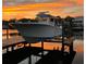 Modern boat lift featuring a large motorboat docked, clear water, and sunset skies at 3225 Bluff Blvd, Holiday, FL 34691