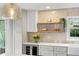 Bright kitchen featuring gray cabinets, quartz countertops, floating wood shelves, and stainless steel wine fridge at 3225 Bluff Blvd, Holiday, FL 34691