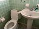 This bathroom has a standard toilet and pedestal sink with matching green tile at 3923 W Bay View Ave, Tampa, FL 33611