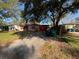 Single-story home with a red metal roof, a gravel driveway, and trash and recycle receptacles at 3923 W Bay View Ave, Tampa, FL 33611