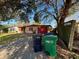 Single-story home featuring a red garage door, a gravel driveway, and trash receptacles at 3923 W Bay View Ave, Tampa, FL 33611