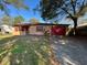 Inviting single-story home with red shutters, a metal roof, and a gravel driveway at 3923 W Bay View Ave, Tampa, FL 33611