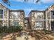 View of tan condo buildings with stairs between, green bushes and a blue sky at 9481 Highland Oak Dr # 703, Tampa, FL 33647