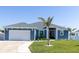 Charming blue home featuring a well-manicured lawn, palm tree, and attached two-car garage at 357 Rallus Rd, Venice, FL 34293