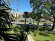 Community view of parking spots, tennis court, and the complex behind trees and landscaping at 1813 Mariner Dr # 152, Tarpon Springs, FL 34689