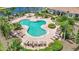Aerial view of resort style pool, lush landscaping, comfortable lounge chairs and elegant clubhouse in the background at 23819 Collina Way # 011101, Port Charlotte, FL 33980