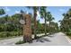 Community entrance with large stone monument sign along a palm tree lined road at 23819 Collina Way # 11201, Port Charlotte, FL 33980