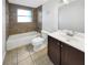 Well-lit bathroom with a tub and shower, featuring neutral tile and dark vanity, offering a clean and functional space at 4508 Golfwood Blvd, Tampa, FL 33634