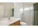 Well-lit bathroom featuring wood vanity, white sink, toilet, and tiled shower with curtain at 6977 74Th Street E Cir, Bradenton, FL 34203