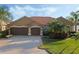 Charming single-story home with a three-car garage, tile roof, and lush landscaping at 6977 74Th Street E Cir, Bradenton, FL 34203