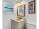 Well-lit bathroom featuring a framed mirror with decorative lighting, complemented by neutral-colored walls at 3084 Williamsburg St, Sarasota, FL 34231