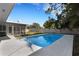 Backyard view with a sparkling blue swimming pool, surrounded by a concrete patio and lush green trees at 3084 Williamsburg St, Sarasota, FL 34231