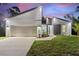 Modern home with a stylish gray and white exterior, two-car garage, and landscaped lawn at dusk at 4044 Simkins Ave, North Port, FL 34286