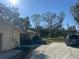 Outdoor shot of the driveway area with a parked car and view of the house exterior and surrounding trees at 7306 Jones Rd, Odessa, FL 33556