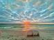A serene beach scene at sunset with calm waters and a bench facing the horizon at 10111 Yacht Club Dr, Treasure Island, FL 33706