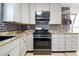 Renovated kitchen featuring white cabinets, stainless steel appliances, and decorative backsplash at 1321 Groveland Ave, Venice, FL 34285