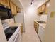 Galley-style kitchen includes tile flooring, black microwave, wood cabinetry, and white appliances at 4034 Dream Oak Pl # 104, Tampa, FL 33613