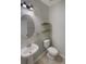 Well-lit powder room with a pedestal sink, toilet, and decorative shelves at 6525 Dutton Dr, Wesley Chapel, FL 33545