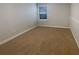 A vacant bedroom with neutral walls, plush carpeting, and bright natural light from the window at 6525 Dutton Dr, Wesley Chapel, FL 33545